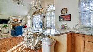 Une cuisine dotée d’un plan de travail en marbre, de meubles en bois, d’un ventilateur de plafond et d’un lustre.