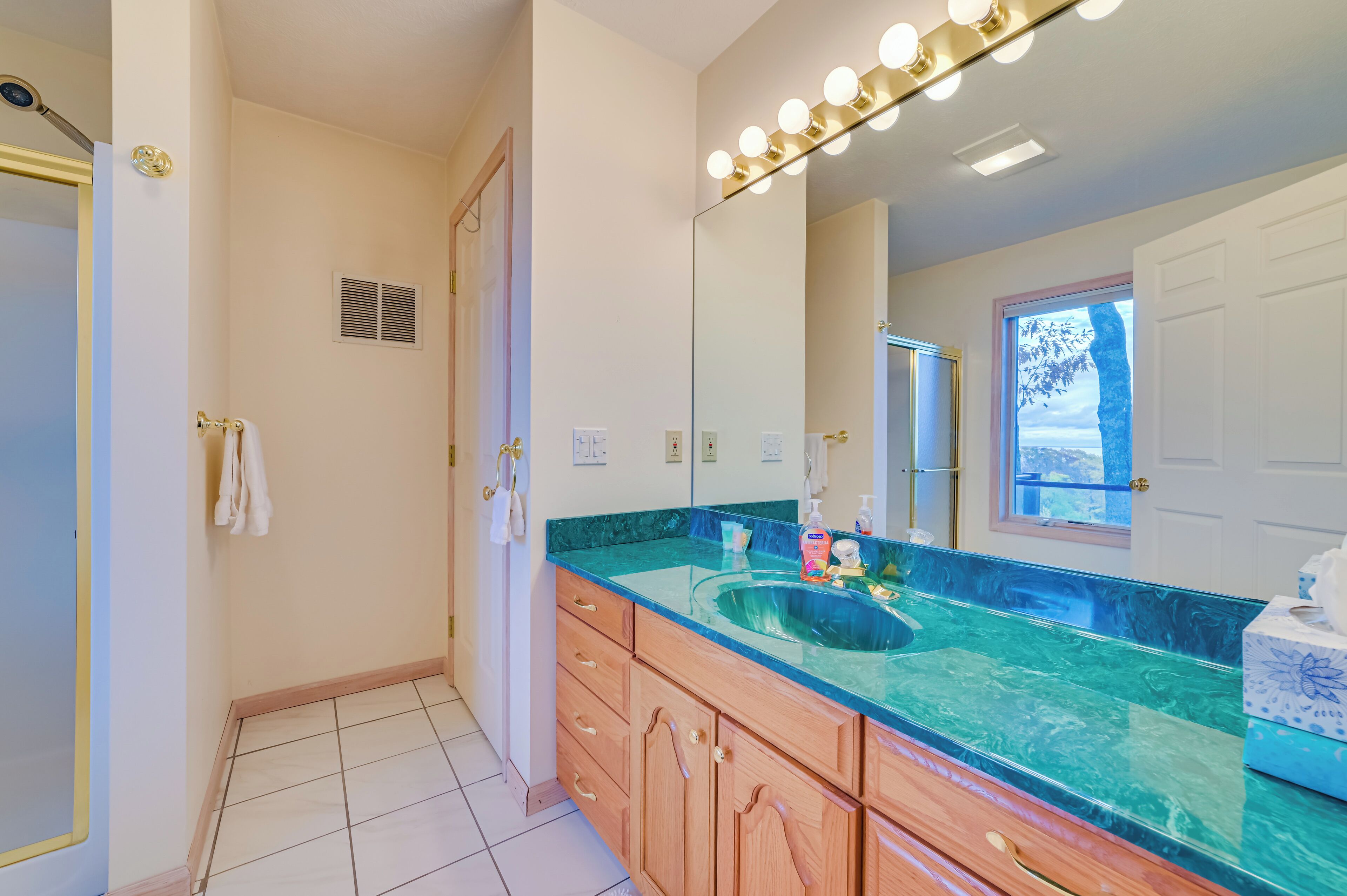 A bathroom with a large mirror, vanity, and a sink.