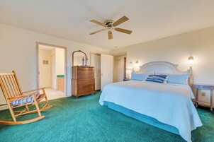 A bedroom with a bed, a rocking chair, a dresser, and a ceiling fan.
