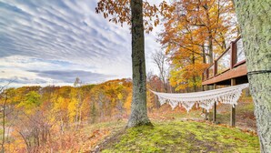 A hammock between trees in a forested area with a wooden deck. - 17 Mi to Skiing! Lake-view Michigan Home w/ Deck (Harbor Springs)