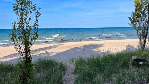 A beach with a sandy path leading to the water, surrounded by grass and small trees. - Sunset Landing - Private Sandy Beach, Lamkin Drive 3 BD, 2 BATH (Sleeps 6) (Harbor Springs)