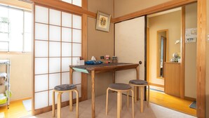 Una stanza tradizionale giapponese con pavimento in tatami, un tavolino in legno e tre cuscini tatami come sedute.