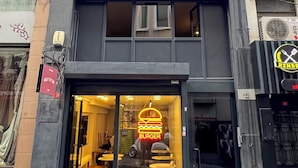 Un edificio con restaurante en la planta baja, con un letrero de neón con forma de hamburguesa y entrada de vidrio.