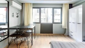 Ein modernes Zimmer mit Esstisch, Stühlen, einem Bett und einem Kleiderschrank.