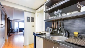 Eine moderne Küche mit schwarzem Arbeitsplatz, Spüle aus Edelstahl und Geschirrgestell. Im Hintergrund ist ein Essbereich mit Tisch und Stühlen zu sehen.