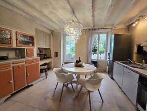 Una cocina con una mesa redonda, sillas, armarios, un refrigerador y una ventana con vistas.
