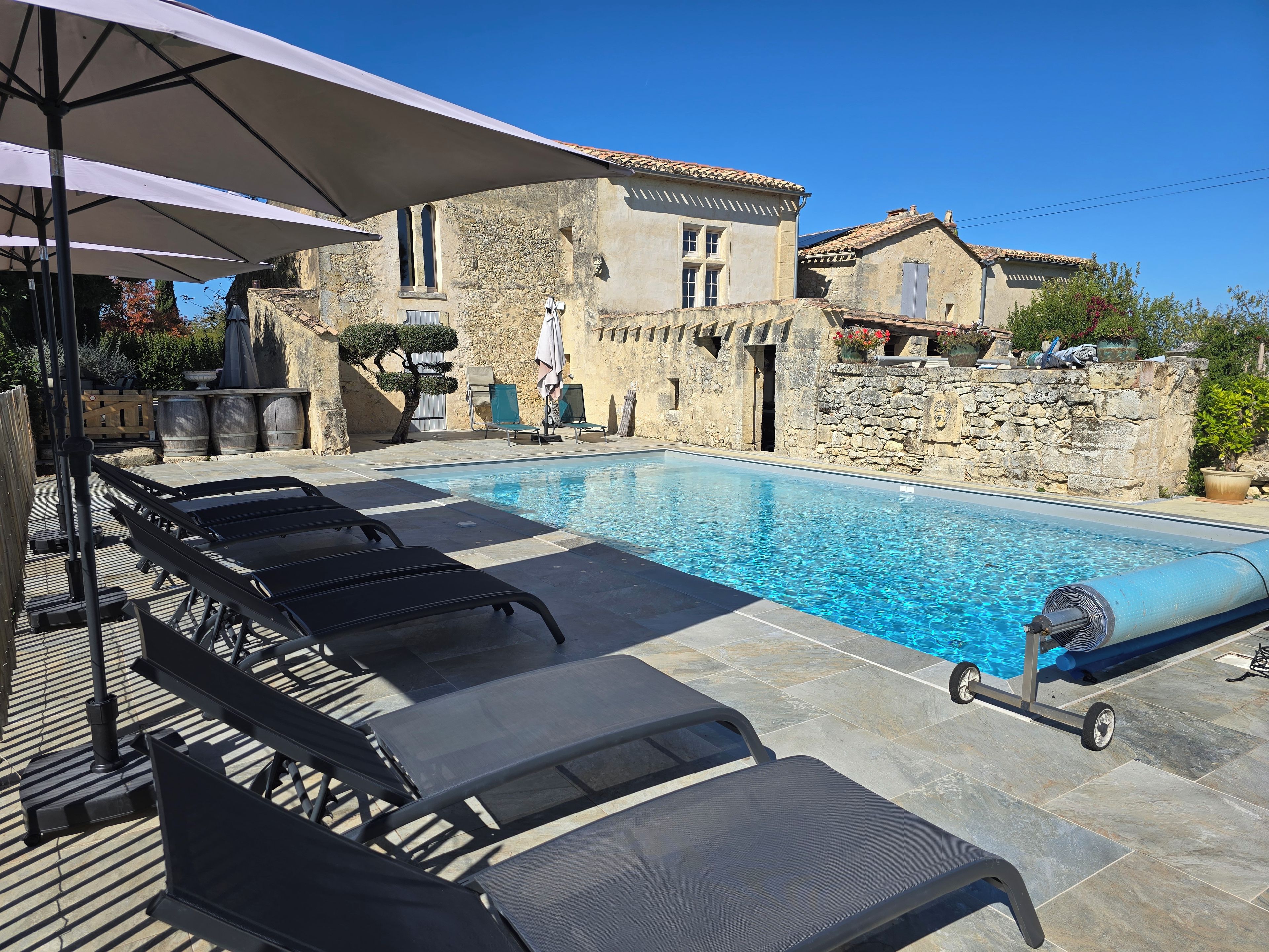 A swimming pool with lounge chairs and a stone wall.