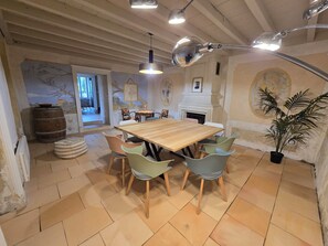 A dining area with a wooden table and chairs, a potted plant, and a fireplace. - Bello Viso, Proche Saint Emilion Dans un Écrin de Verdure au Milieu des Vignes (Belvès-de-Castillon)