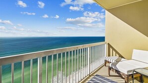 Un balcon avec vue sur l’océan, un canapé blanc et une petite table.