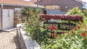 A house named 'HOUSE TOMAS' with a tiled roof, a brick wall, and a garden with red flowers. - Gemütliches Pool House Tomas, in der Nähe von Pula, mit 2 Schlafzimmern (Marčana)