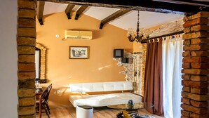 A living room with a white sofa, a glass coffee table, and a stone wall. - Gemütliches Pool House Tomas, in der Nähe von Pula, mit 2 Schlafzimmern (Marčana)
