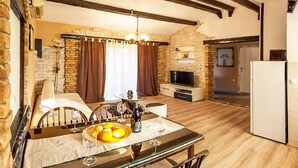 A cozy living room with a stone wall, a fireplace, a TV, and a dining area with a glass table and chairs. - Gemütliches Pool House Tomas, in der Nähe von Pula, mit 2 Schlafzimmern (Marčana)