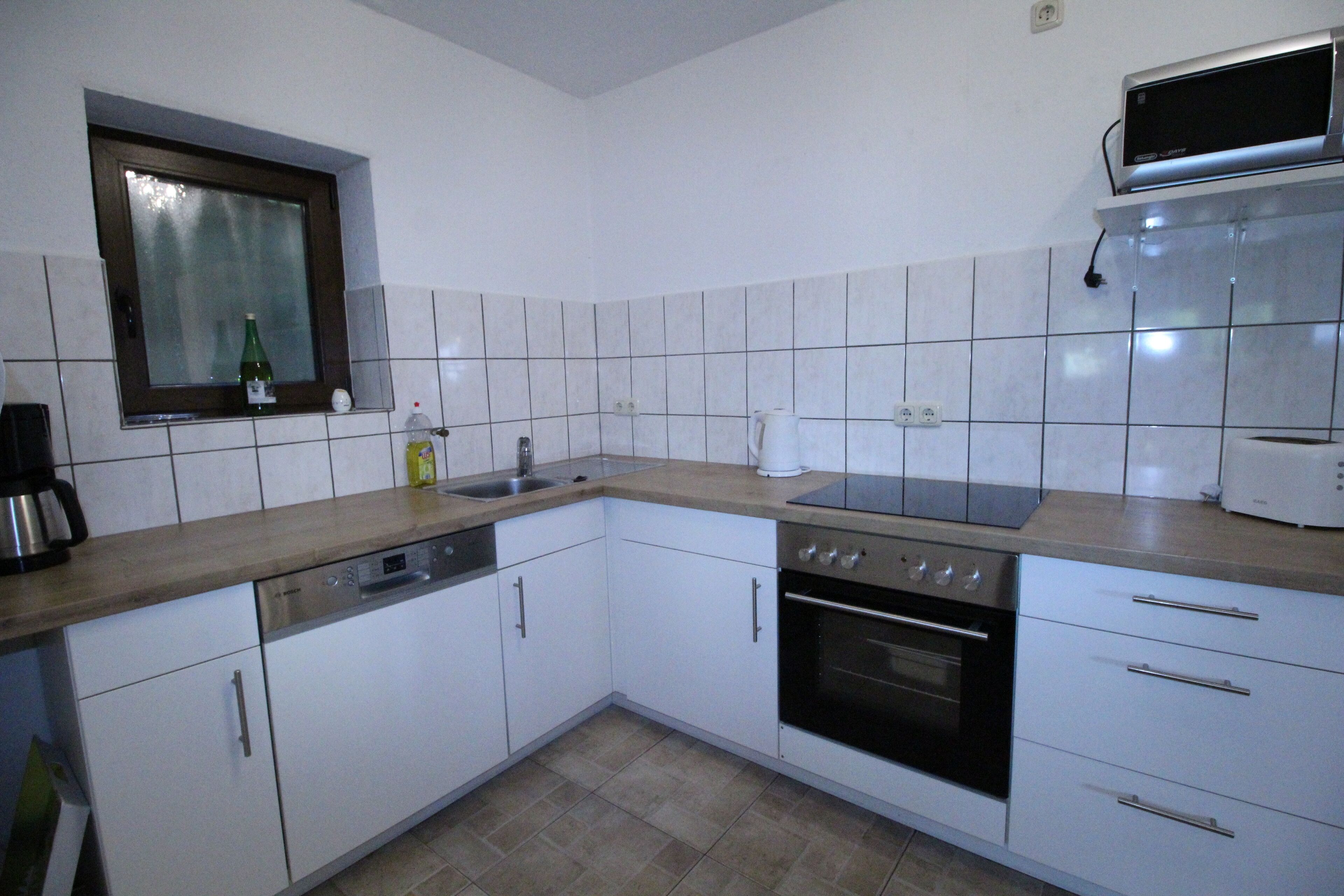 A kitchen with white cabinets, a microwave, a stove, and a sink.