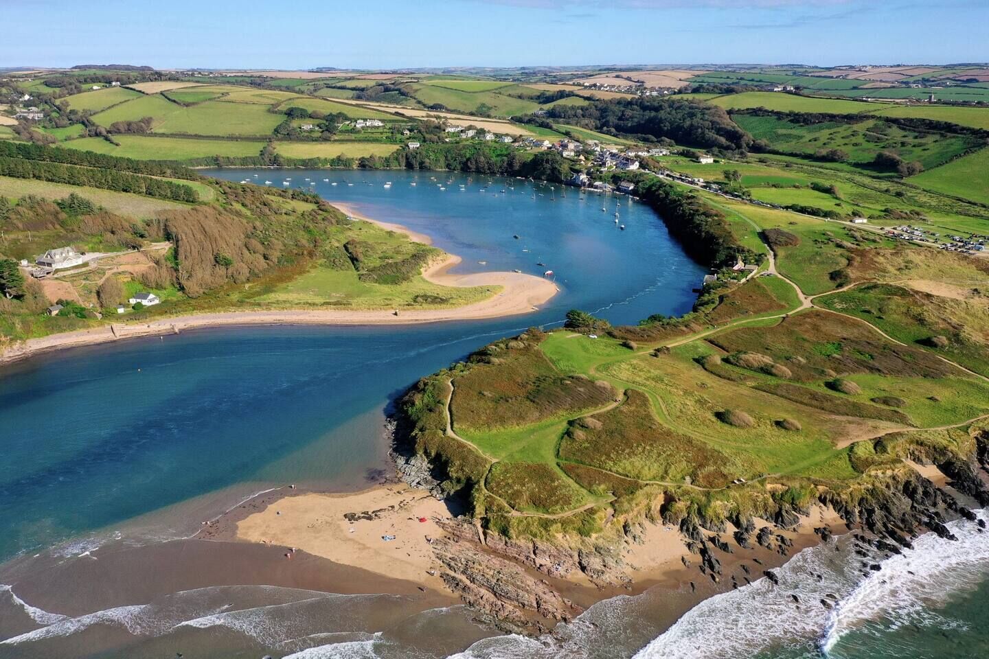 Un paisaje costero con río, playa y campos circundantes.