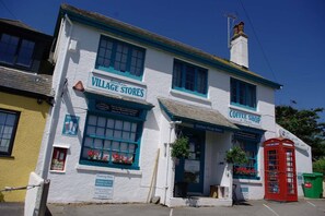 A building with signs for 'Village Stores' and 'Coffee Shop' with a traditional design, including a red telephone booth.