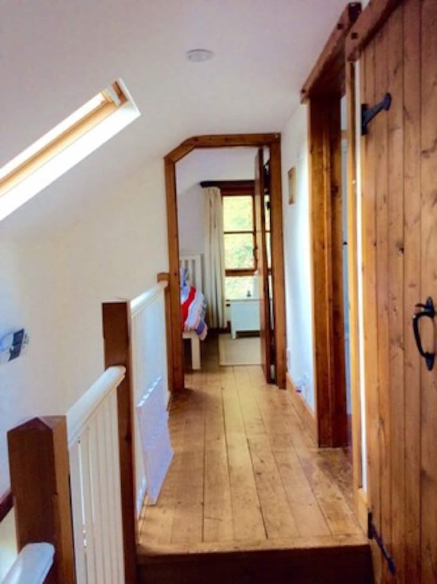 A narrow wooden hallway with a sloped ceiling and a radiator on the left.