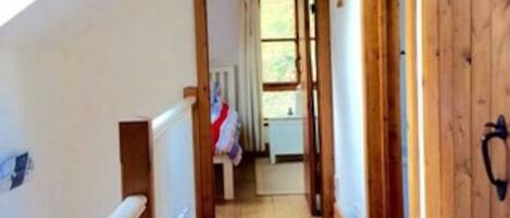 A narrow wooden hallway with a sloped ceiling and a radiator on the left.
