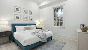 A bedroom with a bed, bedside tables, a window, and framed pictures on the wall.