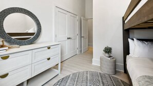 Une chambre à coucher moderne avec un lit, un miroir rond, une commode et une armoire.