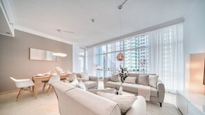 A spacious living room with a dining area, large windows, and modern furnishings. - Colossal 2BR at MAG 218 Dubai Marina by Deluxe Holiday Homes (Dubai)