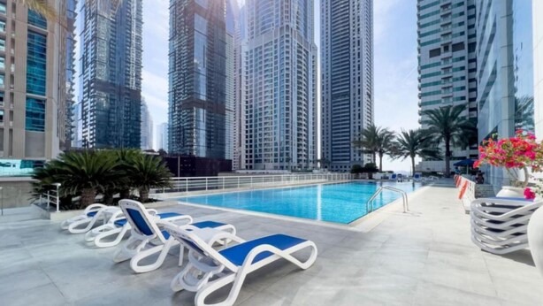 A rooftop pool area with lounge chairs, surrounded by high-rise buildings. - Colossal 2BR at MAG 218 Dubai Marina by Deluxe Holiday Homes (Dubai)