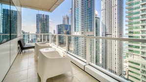 A balcony with a view of high-rise buildings, a white table, and a black chair. - Colossal 2BR at MAG 218 Dubai Marina by Deluxe Holiday Homes (Dubai)