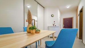 Een vergaderruimte met een houten tafel, blauwe stoelen, een potplant, een klok en een deur.
