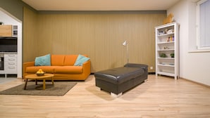 Een moderne woonkamer met een bank, een poef en een boekenkast.