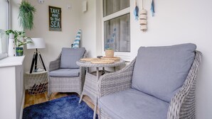 Una habitación acogedora con muebles de mimbre, una alfombra azul y una ventana con detalles decorativos.