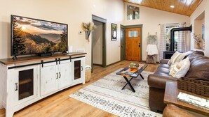 Ein Wohnzimmer mit Fernseher, einer Ledersofa und einem Holzkabinett.