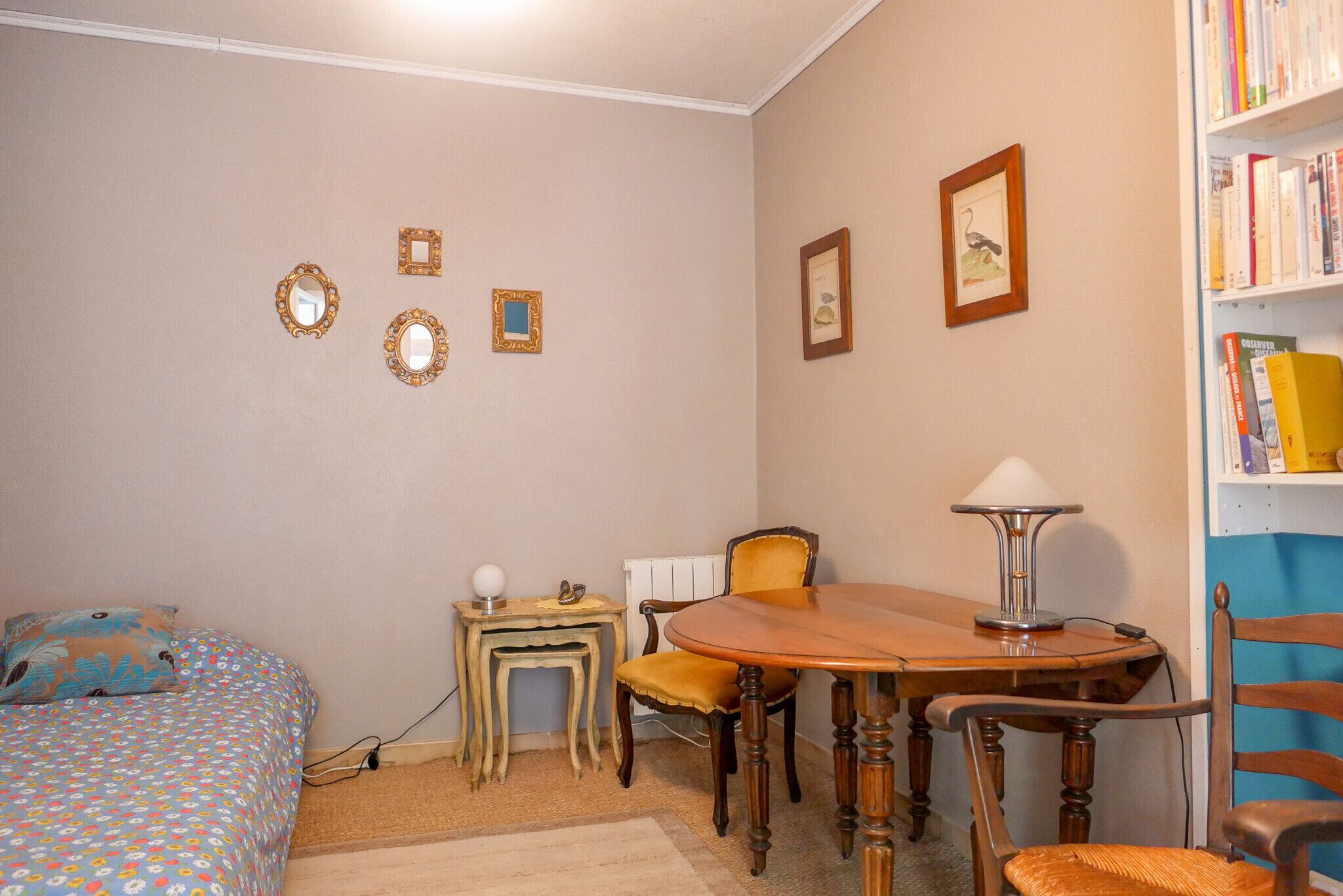 Ein Schlafzimmer mit Bett, kleinem Tisch, Stuhl, rundem Tisch und Bücherregal.