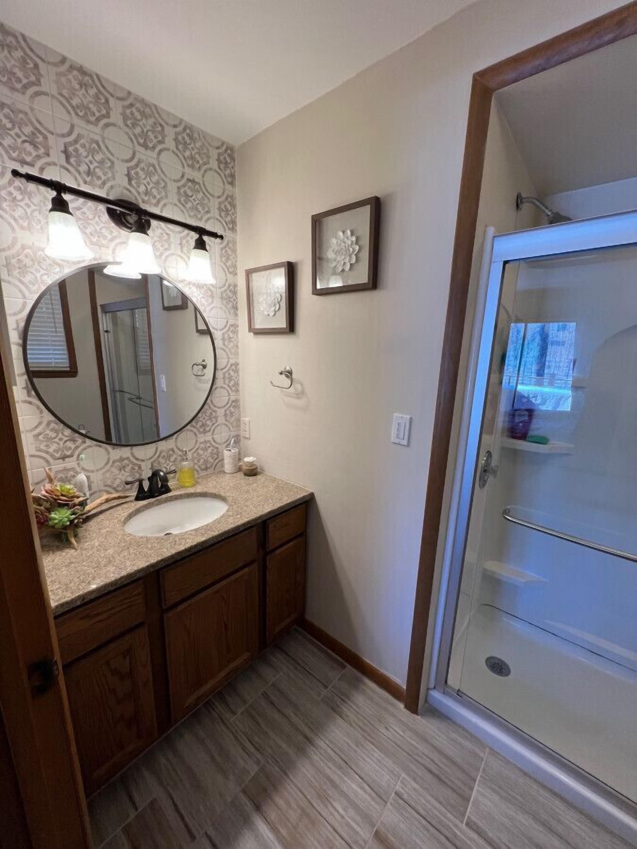 A bathroom with a vanity, a large mirror, a shower, and a toilet.