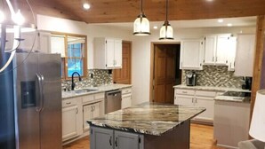 A modern kitchen with a central island, wooden flooring, and pendant lighting. - Hickory Hideaway on Tim`s Ford Lake, Boat rental available (Winchester)