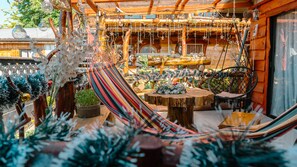 A hammock in a wooden cabin with rustic decor, including a wooden table and hanging lights. - Hostal Central Panguipulli (Panguipulli)