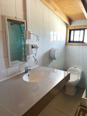 A bathroom with a white sink, a mirror, a hairdryer, and a toilet. - Hostal Central Panguipulli (Panguipulli)