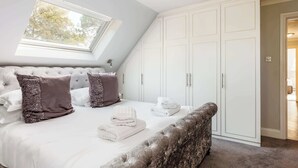 A bedroom with a large bed, a wardrobe, and a skylight. - The Gables Penthouse-Short Walk to Branksome Chine (Poole)