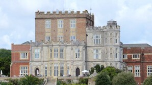 A large, historic building with a prominent tower, multiple windows, and a flag. - The Gables Penthouse-Short Walk to Branksome Chine (Poole)