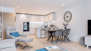 A modern living room with a sofa, ottoman, and a dining area with chairs and a table. - Vitamin Sea - Sun Terrace Overlooking Poole Quay (Poole)