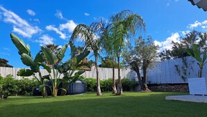 A well-maintained backyard with a lawn, a large inflatable pool, and various tropical plants. - Villasimius Villa Mediterranean Sea... TOP!!! (Simius)