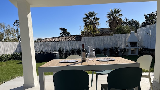 An outdoor patio with a wooden table and two chairs, a wine bottle, and a pitcher. - Villasimius Villa Mediterranean Sea... TOP!!! (Simius)