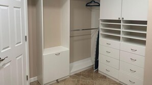 Un vestidor amplio con puertas abiertas, una barra para colgar ropa y varios cajones.