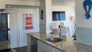 A modern kitchen with a granite countertop, stainless steel appliances, and a built-in sink.