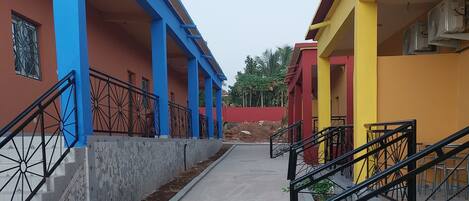 A building with blue and yellow exterior walls, a concrete pathway, and metal railings.