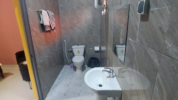 Un baño moderno con un lavamanos blanco, dos inodoros, un espejo y un perchero para toallas.