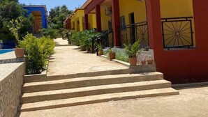 Une rangée de bâtiments jaunes et rouges, avec un chemin de pierre menant à une piscine.