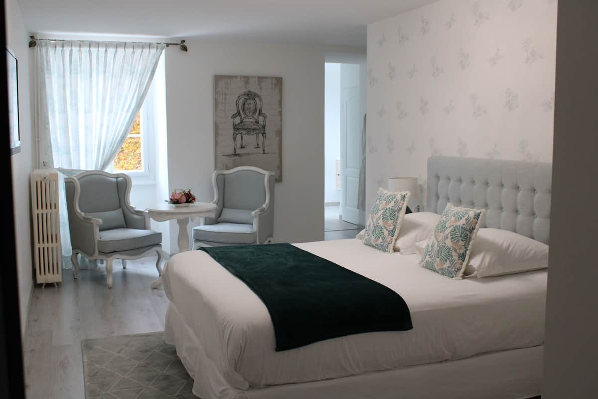 Ein Schlafzimmer mit einem großen Bett, zwei Stühlen, einem kleinen Tisch und einem Heizkörper.