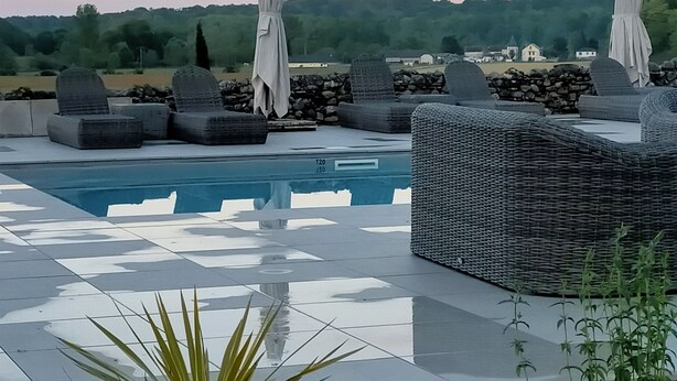 Uma área de piscina no terraço com espreguiçadeiras e guarda-sóis, vista desobstruída da paisagem ao redor e um céu noturno tranquilo.