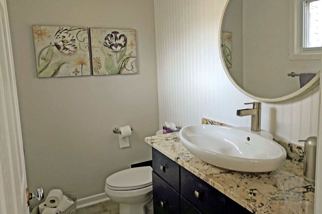 A bathroom with a white sink, dark cabinets, and two floral artwork pieces on the wall.
