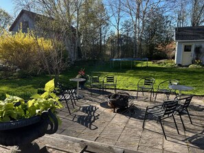Eine Terrasse im Freien mit Steinböden, Metallstühlen, einer Feuerstelle und einem kleinen Tisch.