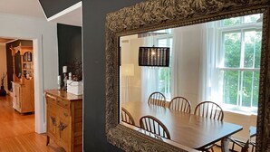 A dining area with a large ornate mirror, wooden furniture, and a view of the outdoors through a window. - Spacious & Charming Century Home - Wellington (Prince Edward)